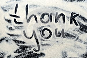 Thank you lettering on a dark, black flour background. Background with inscription.