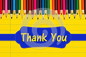 Thank you message with color pencils crayons on yellow ruled line notebook paper