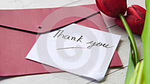 thank you message, envelope and tulip flower on table