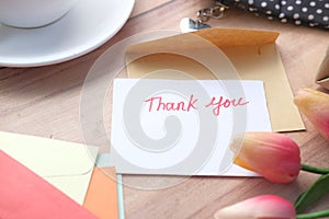 thank you message, flower and envelope on wooden table