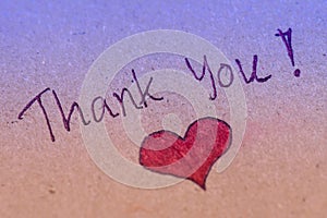 Thank you message with red heart on brown paper.