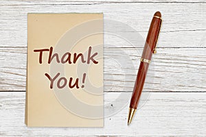 Thank you message on retro old yellowed paper notepad with a pen