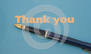 Thank you note on blue paper with pen.