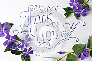 Thank you note surrounded by purple flowers