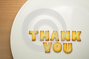Thank you word from alphabet biscuits on white plate