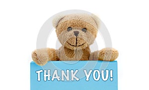 THANK YOU! written on blue card with brown teddy bear holding with the two hands the note with the message.