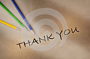 Thank you written on brown paper background with color pencil