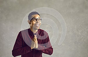 Thankful african american man standing with hands praying looking up studio shot