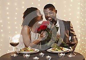 Thankful black lady holding bunch of roses, kissing her boyfriend