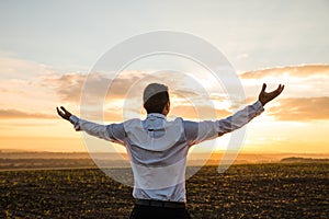 Thankful Businessman with Open Arms at the Field on sunset.