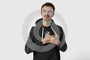 Thankful caucasian young man looking into the camera with hands on his heart. Isolated on white background.Gratitude concept