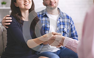 Thankful couple handshaking with specialist at counselor office