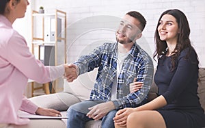Thankful couple handshaking with specialist at counselor office