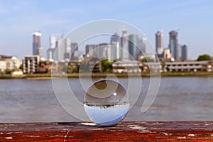 Thankful glass ball looks everything bigger than it is. View on famous business part of London - Canary wharf. Thames river and