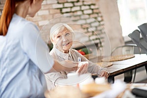 Thankful pensioner smiling while speaking with nurse