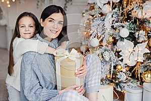 Thankful small female child embraces her mother who gave present