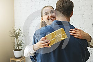 Thankful woman with gift box hugging husband at home. birthday or anniversary surprise