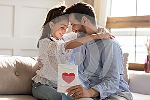 Thankful young father holding handmade greeting card, cuddling daughter.