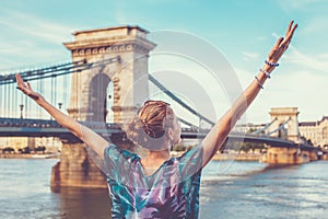 Thankful young redhead woman arms raised at Chain Bridge, Budapest