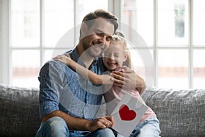 Thankful young smiling handsome daddy embracing little daughter.