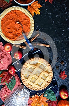 Thanksgiving apple and pumpkin pies on dark marble background.