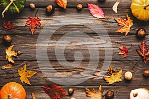 Thanksgiving or autumn frame. Fall composition with pumpkins, fallen leaves, dry flowers and nuts on wooden background