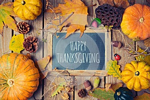 Thanksgiving background with chalkboard. Autumn pumpkin and fall leaves on wooden table.