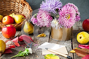 Thanksgiving background with seasonal fruits, flowers, greeting card and envelope on a rustic wooden table. Autumn harvest concept