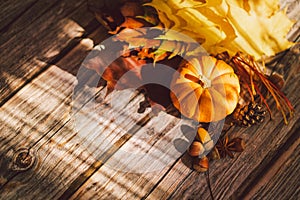 Thanksgiving card. Bouquet of bright yellow red maple leaves and pumpkin on a wooden background
