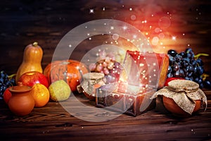thanksgiving concept of pumpkins, apple, garlic, straw and opened chest treasure with mystical miracle light on wooden