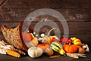 Thanksgiving cornucopia filled with autumn pumpkins and vegetables against dark wood