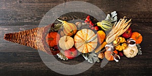 Thanksgiving cornucopia filled with autumn vegetables and pumpkins, above against dark wood