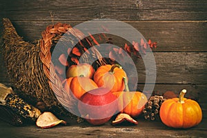 Thanksgiving cornucopia with pumpkins and apples against wood