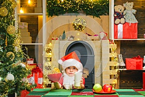 Thanksgiving day and Christmas. Happy Santa Claus - cute boy child eating a cookie and drinking glass of milk at home