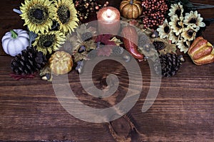 Thanksgiving decor with candle, pine cones, sunflowers, acorns, pumpkins, squash, guard, berries and maple leaves.