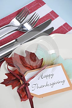 Thanksgiving dining table place setting in modern pale blue, red and white theme - closeup.