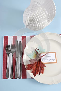 Thanksgiving dining table place setting in modern pale blue, red and white theme - vertical.