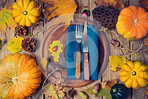 Thanksgiving dinner background with round board. Autumn pumpkin and fall leaves on wooden table.
