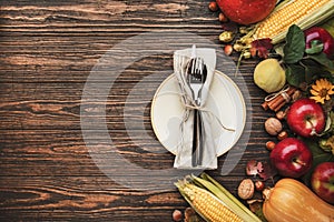 Thanksgiving dinner place setting. Autumn fruit, pumpkins, nuts, fallen leaves with plate and cutlery. Thanksgiving autumn