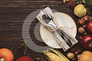 Thanksgiving dinner place setting. Autumn fruit, pumpkins, nuts, fallen leaves with plate and cutlery. Thanksgiving autumn