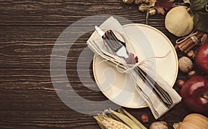 Thanksgiving dinner place setting. Autumn fruit, pumpkins, nuts, fallen leaves with plate and cutlery. Thanksgiving autumn