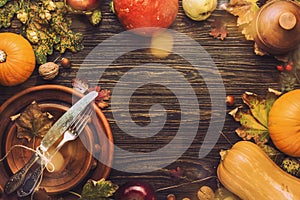 Thanksgiving dinner place setting. Autumn fruit, pumpkins, nuts, fallen leaves with plate and cutlery. Thanksgiving autumn