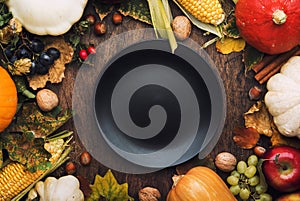 Thanksgiving dinner place setting. Autumn fruit, pumpkins, nuts, fallen leaves with plate and cutlery. Thanksgiving autumn