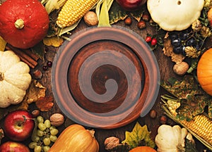 Thanksgiving dinner place setting. Autumn fruit, pumpkins, nuts, fallen leaves with plate and cutlery. Thanksgiving autumn