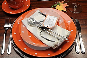 Thanksgiving dinner table place setting with orange plates and Happy Thanksgiving tag