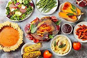 Thanksgiving dinner table with roasted whole chicken or turkey, green beans, mashed potatoes, cranberry sauce, grilled vegetables