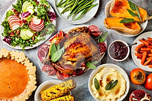 Thanksgiving dinner table with roasted whole chicken or turkey, green beans, mashed potatoes, cranberry sauce, grilled vegetables photo