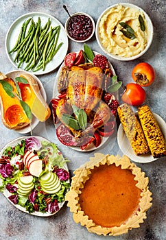 Thanksgiving dinner table with roasted whole chicken or turkey, green beans, mashed potatoes, cranberry sauce, grilled vegetables