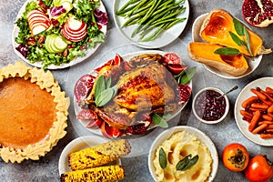 Thanksgiving dinner table with roasted whole chicken or turkey, green beans, mashed potatoes, cranberry sauce, grilled vegetables