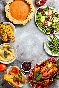 Thanksgiving dinner table with roasted whole chicken or turkey, green beans, mashed potatoes, cranberry sauce, grilled vegetables